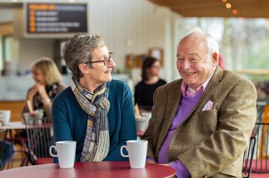 A woman and a man of different ages sit together chatting happily over a cup of tea in our cafe.