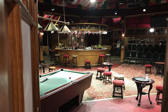 An intimate theatre setting featuring a pool table, small tables, and a circular bar.