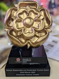 A gold effect statue in the shape of the Visit England Rose, underneath which is engraved "Visit England Awards for Excellence 2022: Ethical, Responsible and Sustainable Tourism Award, Gold Winner 2022, Chichester Festival Theatre"