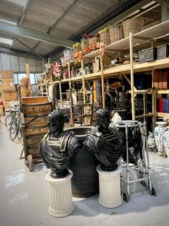 Two black antique busts, blue and white vases, baskets of artificial flowers, wooden trolleys and bicycles are among the items piled high on and next to wooden shelves
