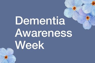 Blue background with graphic forget-me-not flowers in corners. In white text it reads 'Dementia Awareness Week'