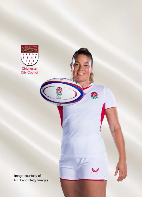 A photo of Jess Breach wearing the England rugby kit; she stands smiling at the camera, holding a rugby ball. The shield of Chichester City Council is at top left.