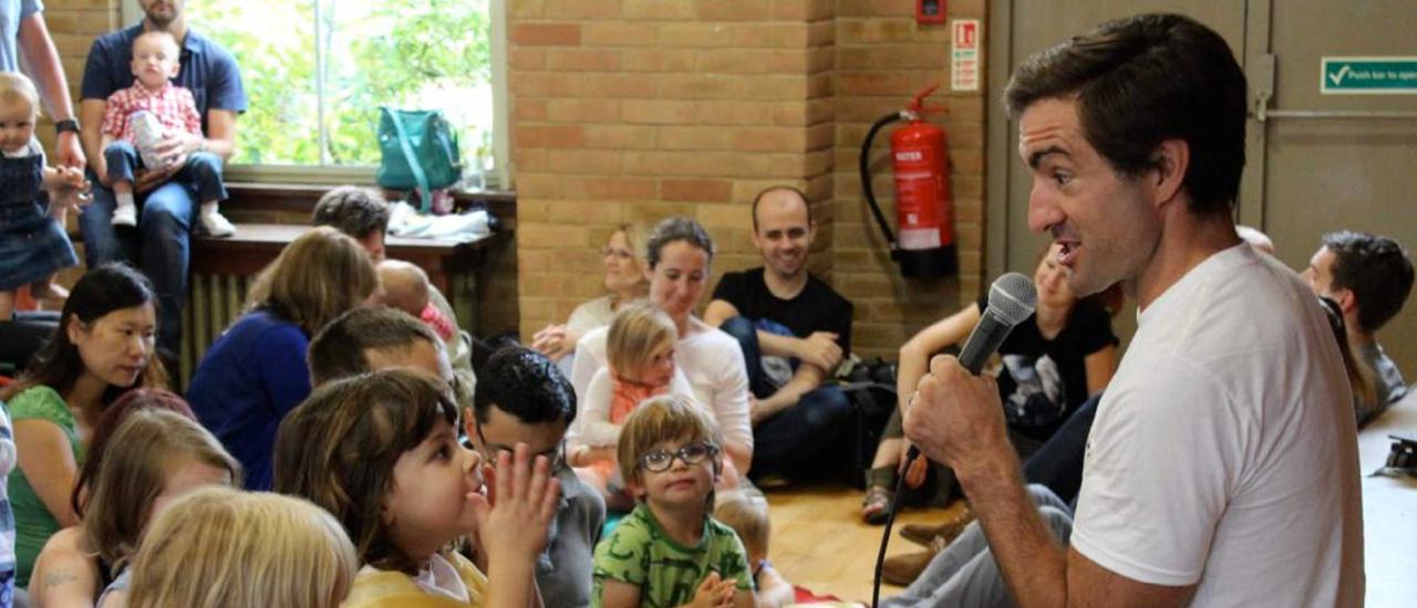 A man with a microphone sings to a groups of children