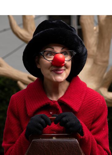 A smiling lady wearing bright red coat and bright red coat, holding a brown handbag.
