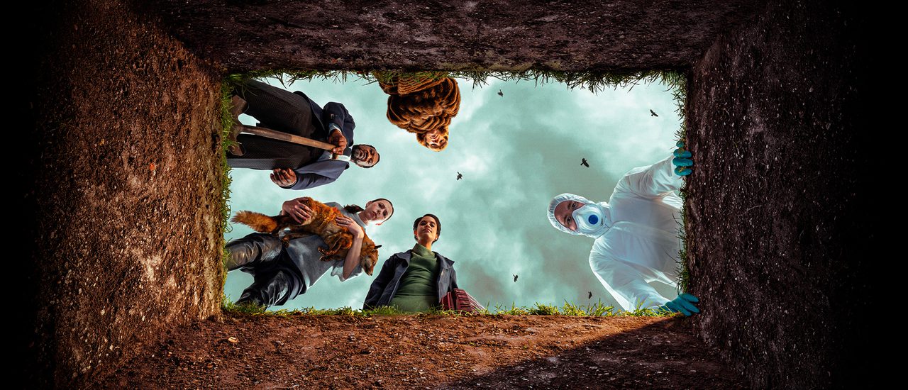 A view from inside a grave looking up at five people gathered around the opening. The group is an eclectic mix: a man in a hazmat suit and mask, a man in a smart suit holding a shovel, a woman cradling a fox, a woman in a fur coat, and another woman dressed formally. Above them, a cloudy sky is scattered with crows.