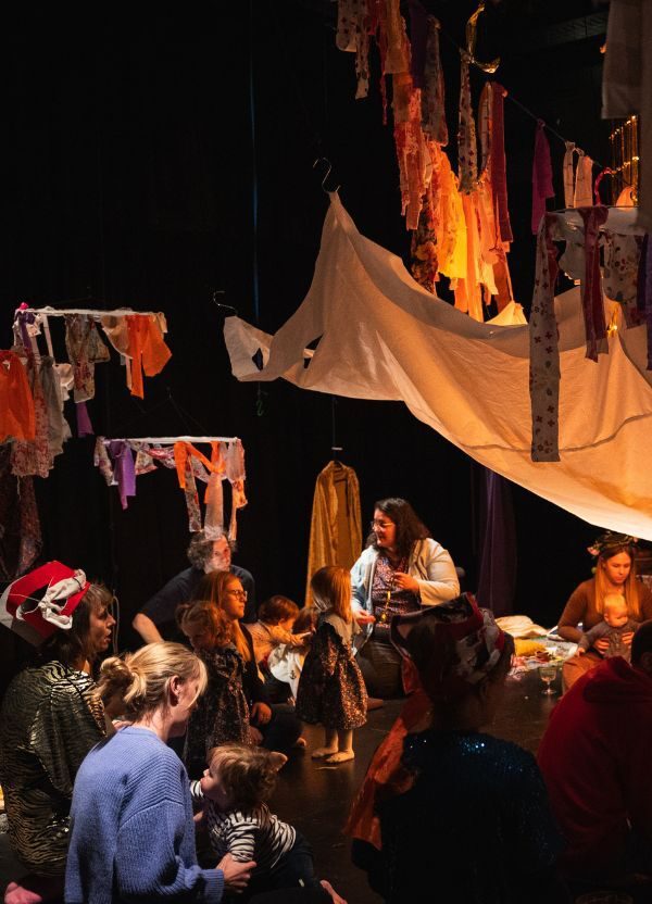 Parents and children in a dark tent like space; atmosphere warm lights illuminate colourful bunting.