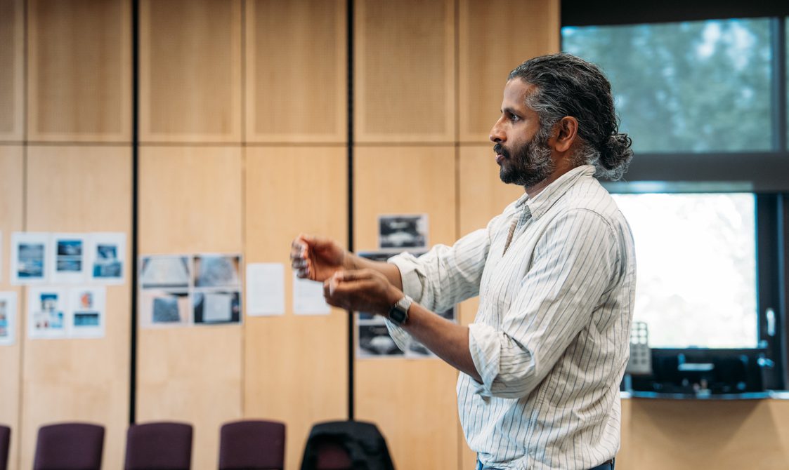 A man is gestures with his arms as he speaks.