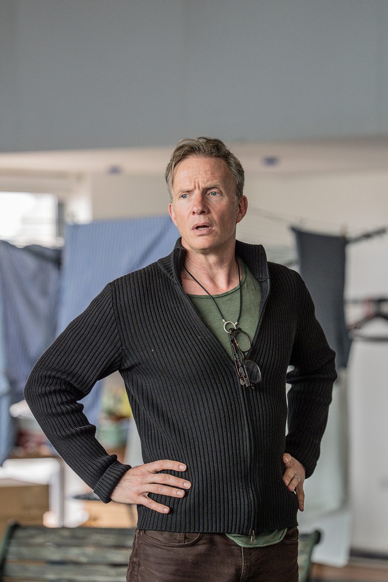 A man stands with his hands on his hips looking exasperated.