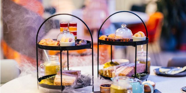 Two afternoon Teas on tiered plates; balloons, tea and frobscottle in the foreground.
