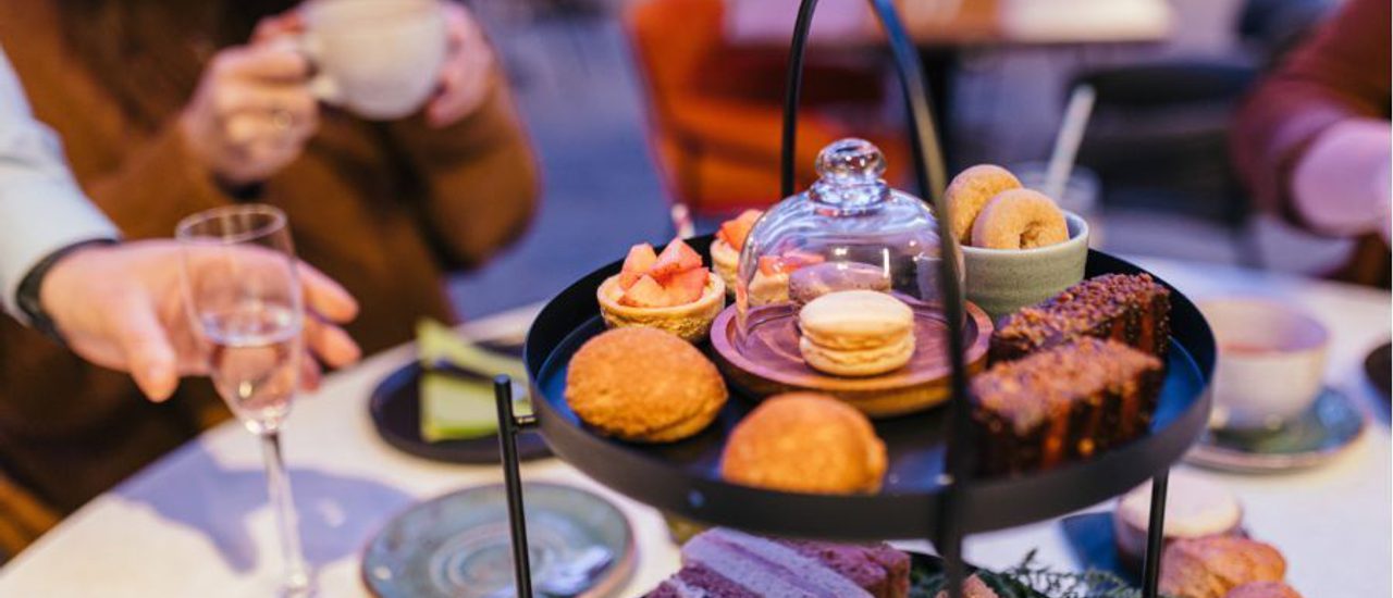 A close up of the Afternoon Tea sweets and sandwiches on a black tiered stand.