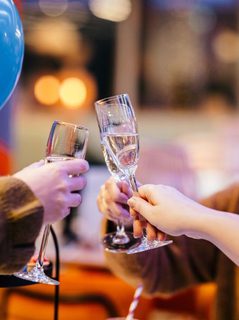 Three women clink their glasses together at a table
