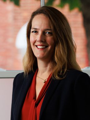 A woman with medium length dark blonde hair smiles confidently.