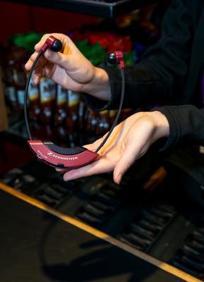 An usher holds an audio description headset in her hands as she passes it to a user.