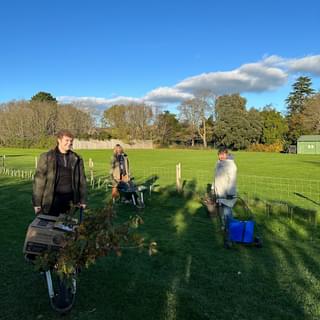 Volunteers planting whips on Oaklands Park, everyone is wrapped in coats and scarves but still smiling.