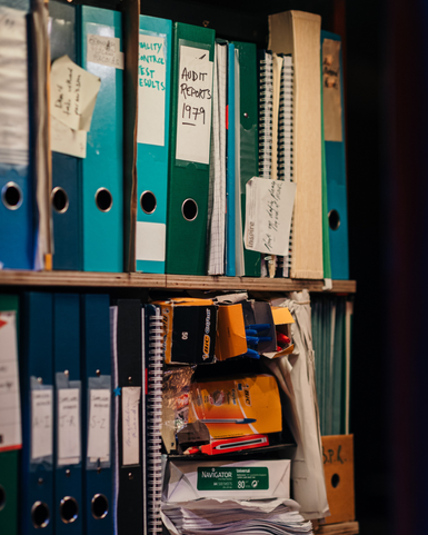 A filing cabinet packed with ring binders, papers and stationary.