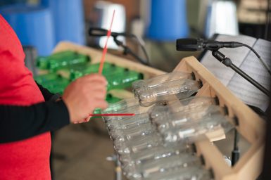 A musician plays an instrument made from plastic bottles.