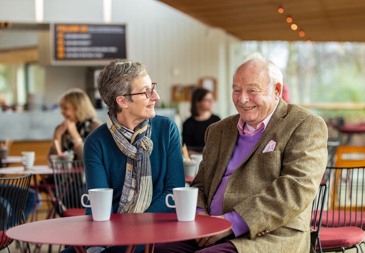 A man and a woman sitting together in our café enjoying a cup of tea and laughing together