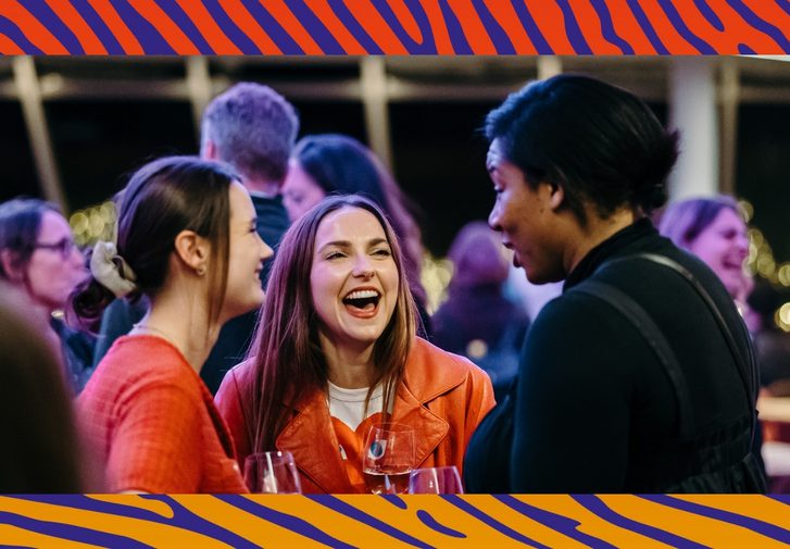 A group of friends making each other laugh in the Minerva bar. The image has a blue and orange thumbprint border.