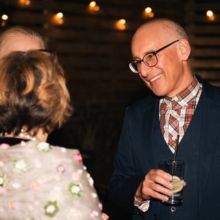 A man (in a suit jacket and shirt) smiles warmly at a woman (with a cream shawl over her shoulders)