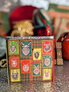 A wall from a set model box show a gallery of reindeer portraits on a tartan wall. behind is an assortment of props from the Grotto in red, green and gold.