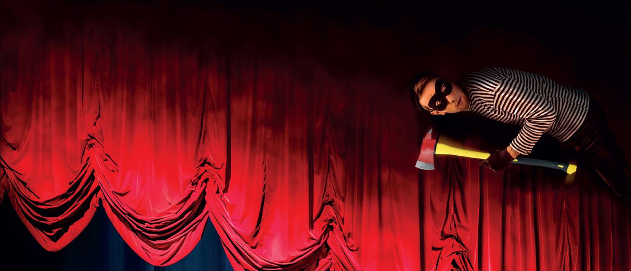 A traditional red velvet stage curtain hangs in haphazard, lopsided loops above a stage. In the top right corner of the image is a man in a black and white striped top and black bank robbers mask, holding a red handled axe, seemingly hanging from the ceiling.