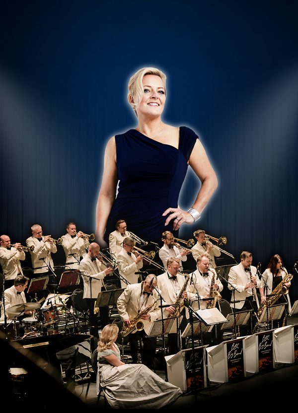 A blonde female singer is positioned above a band of musicians, all playing brass instruments and dressed in white jackets.
