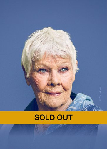 A photo of Dame Judi Dench on an indigo background. She looks off into the distance with a gentle smile. She has a blue scarf with white leaves draped over her shoulders. A yellow banner below her head in block capitals 'SOLD OUT'