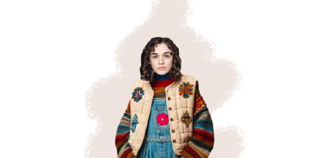 A illustration of a girl in a patchwork costume - cream jacket and blue dungarees with embroidered flowers on.