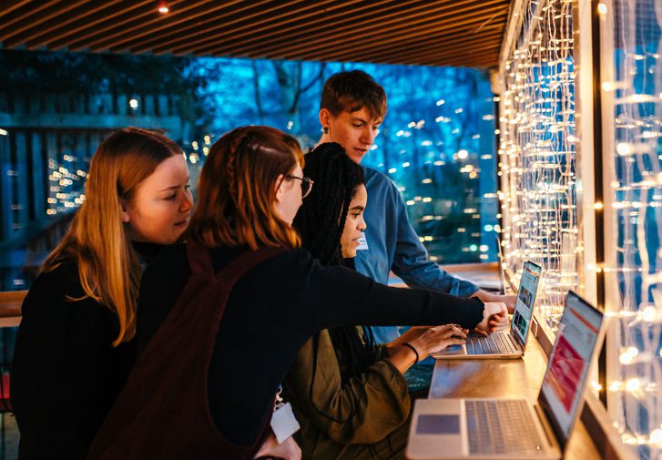 Four members of staff gathered around a computer, working collaboratively.