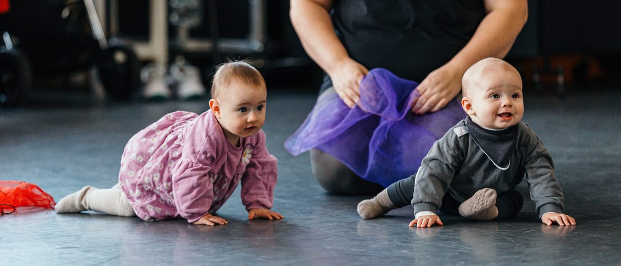 Two little babies are crawling on the floor at a early years.