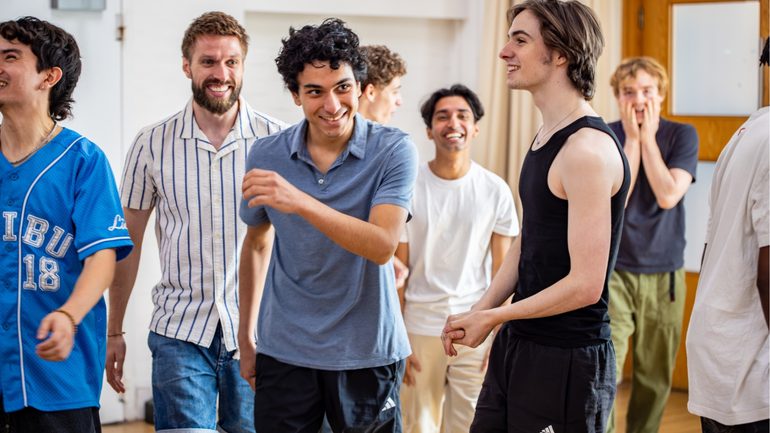 A group of performers are stood smiling.