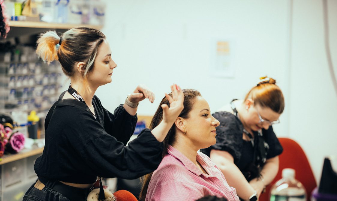 A side view of an actor getting her hair done.