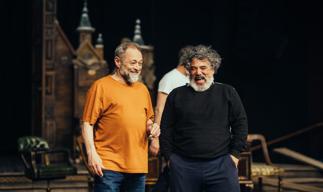 Two actors stood on stage during warm-up makinf each other laugh.