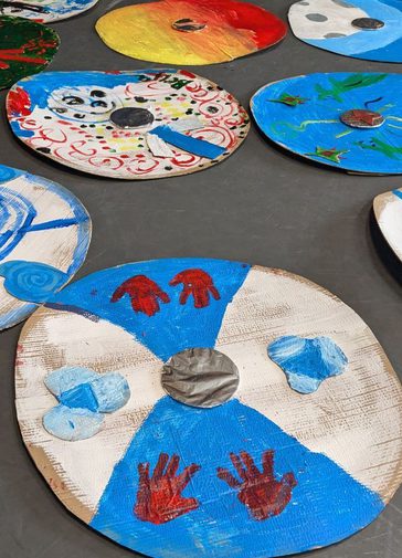 An array of cardboard shields painted in bright colours.