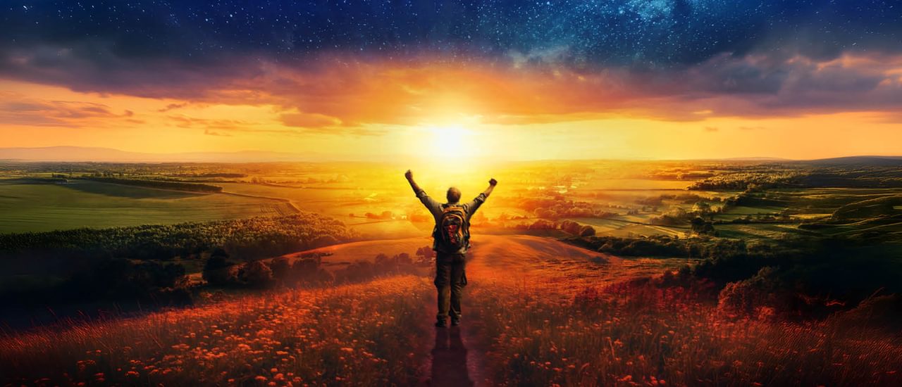 A man stands looking over a wide country landscape, with sunrise illuminating the scenery. Seen from behind, the man's arms are raised in exultation, and he wears a rucksack on his back. A flowery meadow in the foreground slopes away to green fields, woods and distant hills, and the sun is burning away the clouds and remnants of stars; it's an uplifting, rural scene.