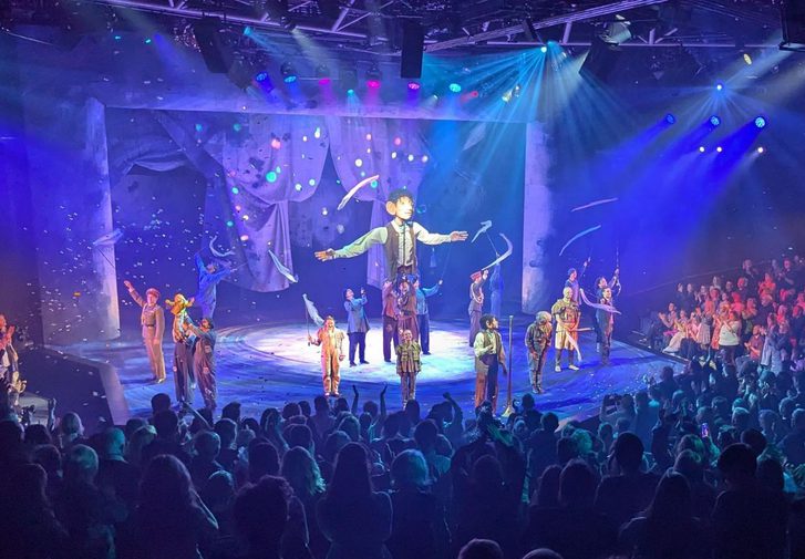 A group of people in casual clothes hold aloft a giant puppet on poles; only the puppet's arms, hands and the lower half of its torso can be seen.