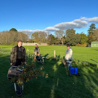 Volunteers planting whips on Oaklands Park, everyone is wrapped in coats and scarves but still smiling.