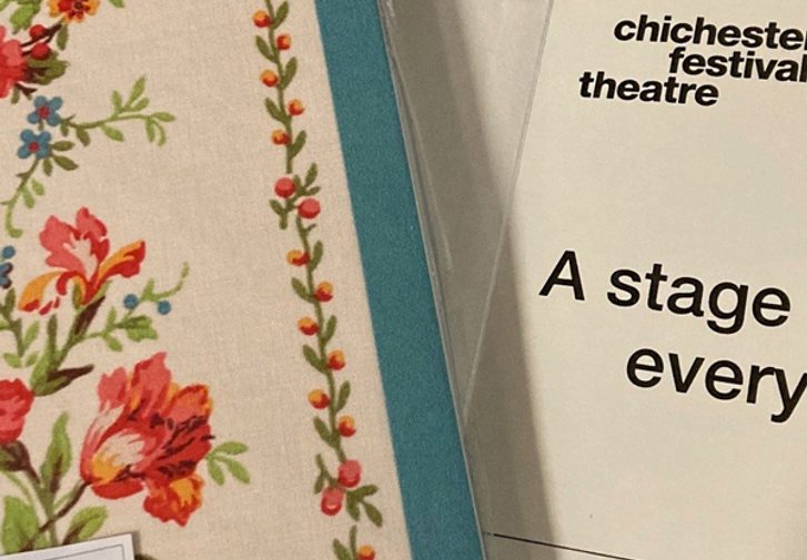 Two hardback notebooks: one is bound in floral fabric, resting on an open notebook page with the Chichester Festival Theatre logo and the words 'A stage for every story'