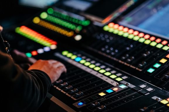 A man's hand moves a lever on a lit up technical desk