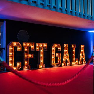 Large lit up letters spelling CFT gala sit next to the exterior wall of the Festival Theatre.