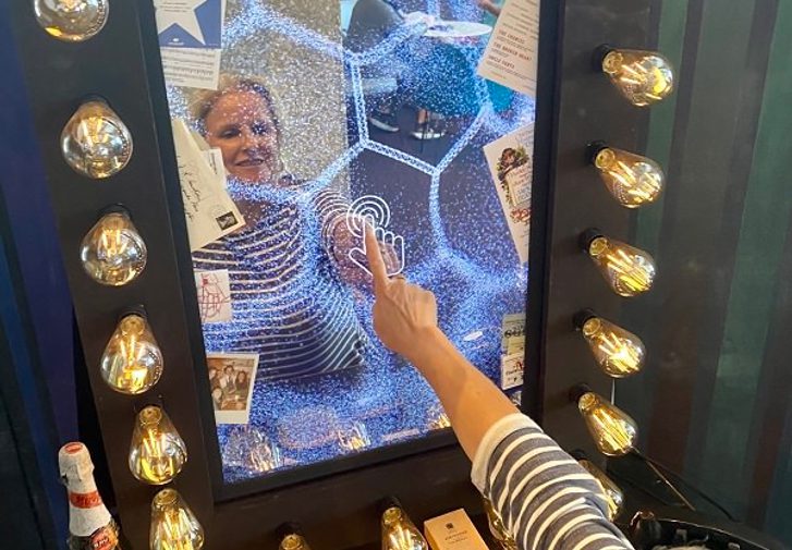 A woman with blonde hair touches an interactive screen