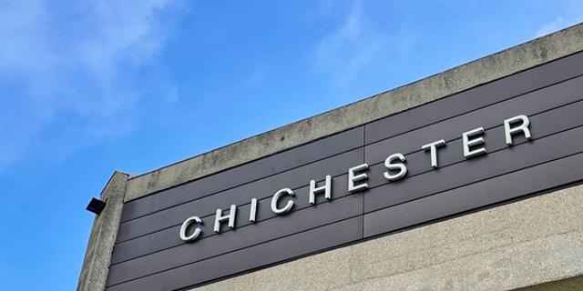 A slice of the concrete façade of the Festival Theatre against a bright blue sky.
