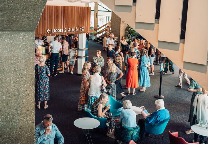 The Festival Theatre foyer is full of people, some sitting, some standing and some waiting for drinks at the bar.
