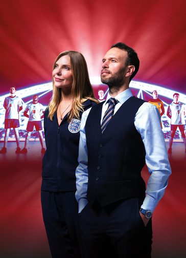 A man and a woman stand beside one another, proudly looking up into the distance. The woman (labelled Samantha Womack as Pippa Grange) wears an England football team tracksuit with the three lions badge. The man (labelled David Sturzaker as Gareth Southgate) wears Southgate's iconic waistcoat over a shirt and tie. The red background features an illuminated stadium with England football players lined up proudly in front of it. Text over the image reads: 'Five stars (The i), 'The decade's biggest theatrical triumph' (Telegraph). The acclaimed National Theatre production: Dear England. A new play by James Graham, directed by Rupert Goold, set design by Es Devlin.'